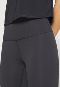 Hochtaillierte schwarze Leggings aus dehnbarem Stoff, mit flachen Nähten, glatter Textur und tailliertem Schnitt.