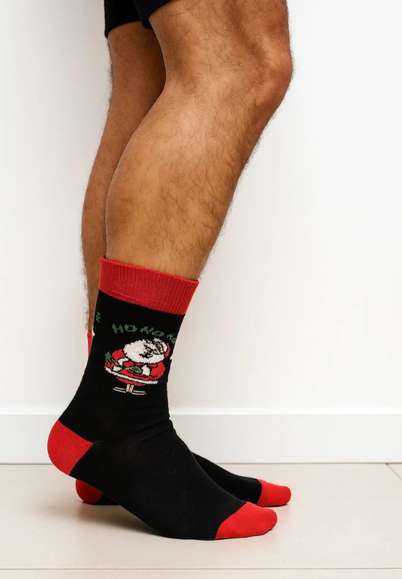 Black socks with red accents, featuring a Santa Claus design and the text "HO HO HO," made from a soft, stretchable material.