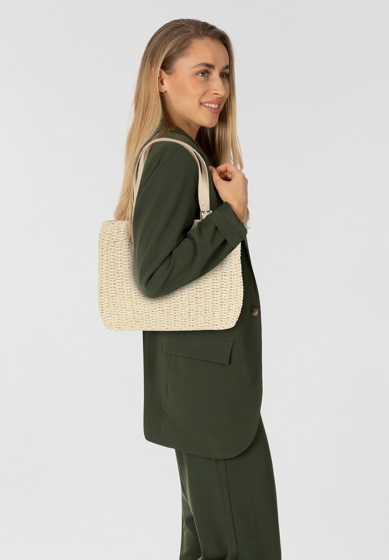 Beige geweven tas met een gestructureerde, rechthoekige vorm. Voorzien van twee schouderbanden en een gestructureerd oppervlak, aangevuld met een neutrale tint.