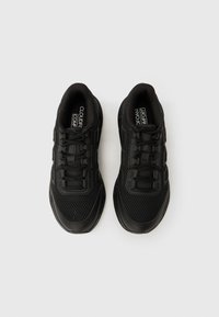 Sorte atletik sko med en mesh-overdel, polstrede kraver, flade snørebånd og en tyk gummisål med tekstureret overflade for bedre greb.