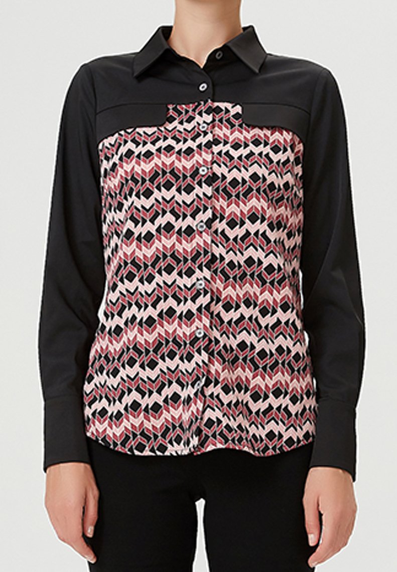 Chemise à boutons avec des manches noires et un devant à motifs en formes géométriques roses, rouges et noires. Col classique et coupe structurée.