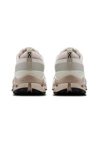 Lichtbeige sportschoenen met een gestructeerde bovenkant, voorzien van een gevoerde kraag, een trekkinglus en een gevoerde zool met een zwart rubberen profiel voor grip.