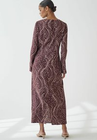 Lång, figurnära klänning i djup burgundy med krämfärgad abstrakt mönster. Långa ärmar, rund halsringning och sidslitsdetalj. Slätt, lättviktsmaterial.