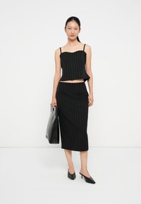 Svart rutete to-dels sett med en cropped tank top med hjerteformet utringning og en midi-skjørt. Tilbehøret inkluderer en svart veske.