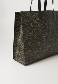Zwarte draagtasje met een groen bladerenpatroon, gemaakt van glad materiaal, met lange zwarte handvaten en een rechthoekige vorm.