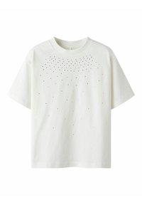 T-shirt en coton blanc avec un col rond et des manches courtes, présentant une dispersion de petits points noirs sur le devant supérieur.