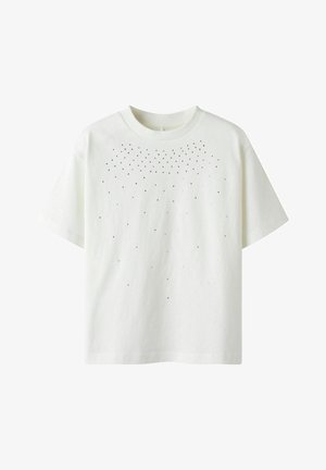 Camiseta de algodón blanca con un escote redondo y mangas cortas, que presenta una dispersión de pequeños puntos negros en la parte superior delantera.
