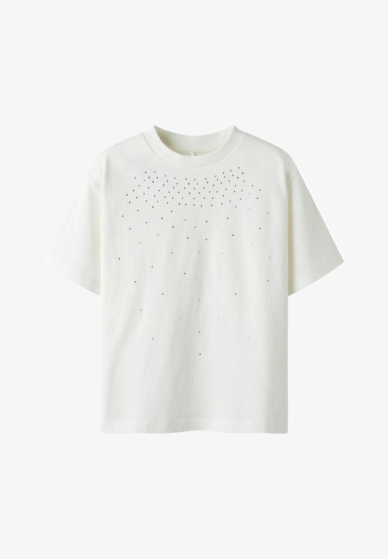 Weißes Baumwoll-T-Shirt mit einem runden Halsausschnitt und kurzen Ärmeln, das über die obere Vorderseite mit kleinen schwarzen Punkten übersät ist.