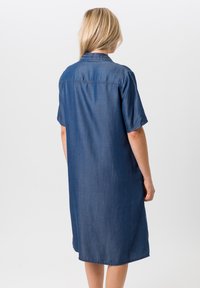 Denim shirtjurk, korte mouwen, lichtblauw, knoopsluiting met kraag, rechte snit, knielang, met een gladde textuur en een minimalistisch ontwerp.