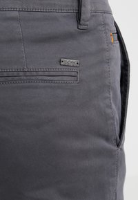 Grå shorts gjorda av lättviktsmaterial med en liten metall "BOSS"-logotyp, fram- och bakfickor samt synliga sömnadsdetaljer.