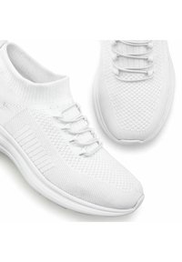 Scarpe da ginnastica bianche con una tomaia in maglia, dotate di un colletto simile a una calza e un sistema di allacciatura visibile, motivo testurizzato e suola flessibile.