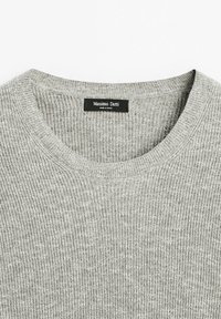 Pull en maille côtelée gris clair avec col rond, portant une étiquette noire indiquant "Massimo Dutti Made in China."
