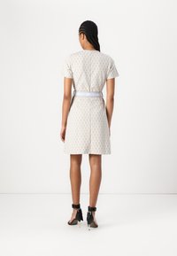 Robe à manches courtes en tissu beige clair avec un motif géométrique et une coupe ajustée, ornée d'une ceinture de marque bleue et d'un ourlet droit.