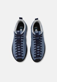 Scarpe da arrampicata blu scamosciate con punte in gomma scura, lacci blu navy e rivestimento in tessuto grigio. Presentano un logo prominente sul lato.