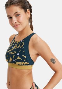Sporty crop top featuring a multicolored design in navy, gold, and purple, made of stretchy material with a solid band at the bottom.