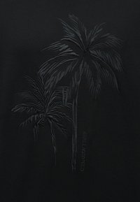 Ανάγλυφο μαύρο ύφασμα με δύο φοίνικες και το κείμενο "KARL LAGERFELD" σε απαλό, ανάγλυφο σχέδιο.