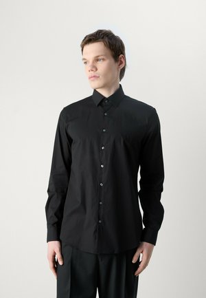 Camicia nera con colletto, maniche lunghe e una texture sottile; presenta bottoni neri e orlo dritto.