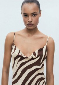 Robe imprimée zèbre brun et crème avec un col drapé et des bretelles fines, présentant une texture lisse et une coupe ajustée.