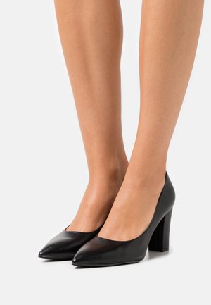 Scarpe con tacco alto in pelle nera, con punta affusolata e tacco largo. Presentano un design minimalista e una texture liscia.