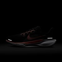 Scarpa sportiva nera con tomaia tessurizzata, dettagli rossi e elementi riflettenti. Presenta una suola ammortizzata e il distintivo emblema Nike.