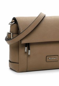 Brown leather crossbody bag with a fold-over flap, silver hardware, and two zipper pulls. Features a logo on the side and an adjustable strap.