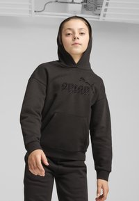 Svart huvtröja med känguruficka, med en texturerad logotyp fram. Materialet verkar mjukt och tjockt, lämpligt för avslappnad användning.