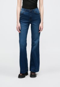 Μπλε τζιν παντελόνι με φαρδύ πόδι σε μέτρια απόχρωση και ψηλή μέση. Διαθέτει μπροστινές τσέπες και κλείσιμο με κουμπιά. Κατασκευασμένο από υφαντό denim.