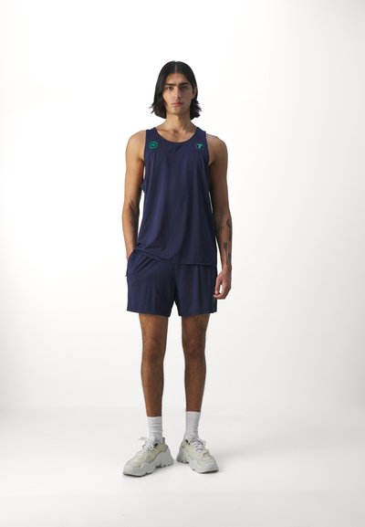 Idrettsantrekk i mørk marineblå, bestående av en tank top og shorts. Laget av lett stoff med grønne logo detaljer. Skoene er lyse grå.