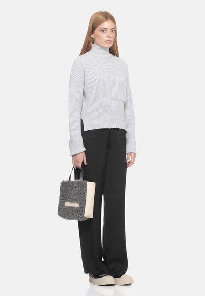 Maglione grigio a coste con collo alto e tasca, pantaloni neri a gamba larga e una borsa pelosa grigio scuro con un accento beige e scritte. Scarpe basse.