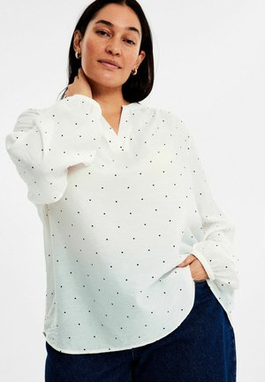 Weiße Bluse mit langen Ärmeln und V-Ausschnitt, gemustert mit kleinen schwarzen Punkten, mit gerafften Puffärmeln und einem lässigen Schnitt.