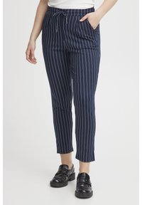 Navy striped trousers with an elastic waistband and drawstring, featuring side pockets and a tapered leg design. Paired with black shoes.