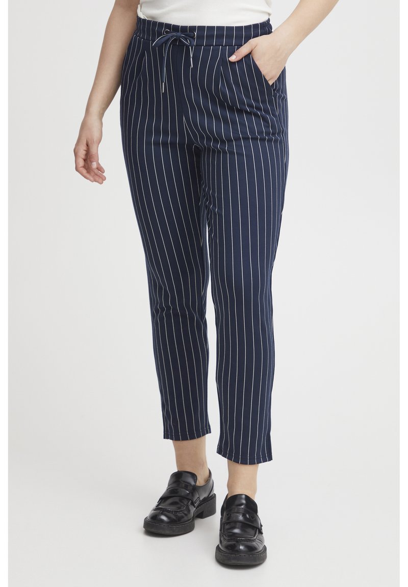 Navy striped trousers with an elastic waistband and drawstring, featuring side pockets and a tapered leg design. Paired with black shoes.