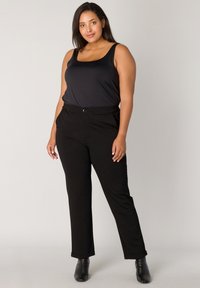 Zwarte tanktop en zwarte broek outfit. De broek heeft een rechte pasvorm, knoopsluiting, een gladde textuur en opgerolde mouwen.