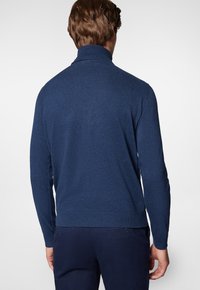 Granatowy sweter dzianinowy z wysokim kołnierzem, ściągaczami na mankietach i u dołu, charakteryzujący się miękką fakturą i dopasowanym krojem.