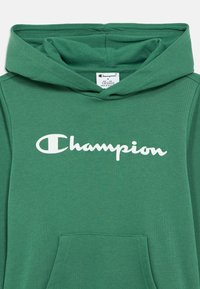 Πράσινο βαμβακερό φούτερ με κουκούλα και τσέπη καγκουρό μπροστά, κουκούλα με κορδόνι και λευκό λογότυπο «Champion» στο στήθος. Μαλακή υφή υφάσματος.