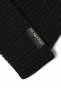 Gorro de lana negro tejido con textura acanalada. Presenta una etiqueta tejida con "JACK & JONES" y "STUDIO COLLECTION" en blanco y gris.