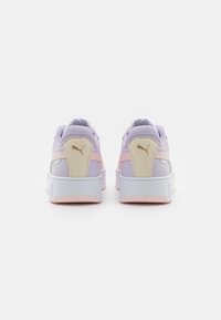 Sneaker Puma con tomaia lilla, dettagli rosa, tallone crema, logo oro e suola bianca con motivo testurizzato.