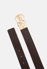Ceinture en cuir texturé marron avec une boucle ronde en or arborant un logo et une finition lisse. Comprend plusieurs trous pour un ajustement.