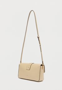 Μπεζ δερμάτινη τσάντα χιαστί με στρογγυλεμένο σχήμα, λεπτομέρειες από χρυσό μέταλλο και καπάκι με διακοσμητικά καρφιά. Περιλαμβάνεται ρυθμιζόμενο λουρί.