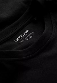 Mustaa puuvillapaitaa, jossa on pyöreä kaula-aukko. Tunnuksessa teksti "ombre", 100 % puuvillaa, koko M/48, valkoista tekstiä kankaan päällä. Tasainen pinta.