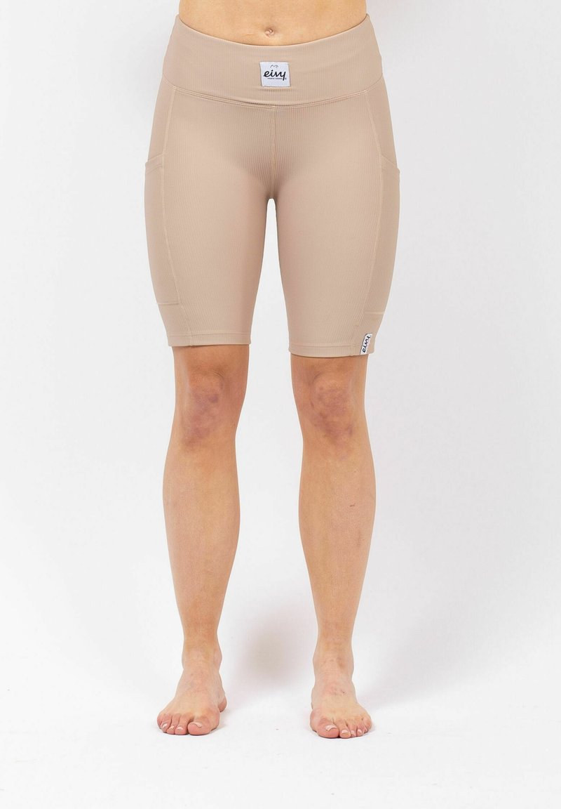 Beige high-waisted fietsshorts van ribstof, met zijzakken en een gladde textuur, met een logo-label op de tailleband.
