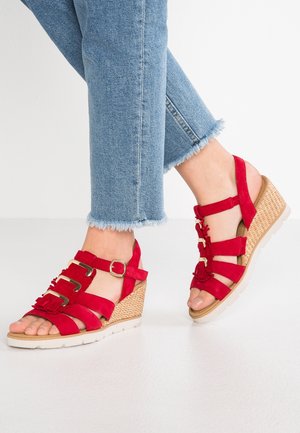 Rode suède wedge sandalen met meerdere banden, een gespsluiting en een geweven basis. De zool is beige met een gestructureerd grip.