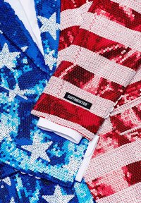 Paillettenblazers in blauw met witte sterren en rood met witte strepen. Beide hebben een satijnachtige textuur en het "SUITMEISTER"-logo op de mouw.