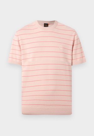 Jasnoróżowa dzianinowa koszulka z krótkim rękawem, wyposażona w cienkie czerwone poziome paski oraz małą kwadratową naszywkę z logo na lewej piersi.