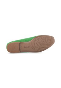 Groene suède platte schoen met een bruine rubberen zool. Heeft een gestructureerd loopvlakpatroon en een gezeefde merknaam op de zool.