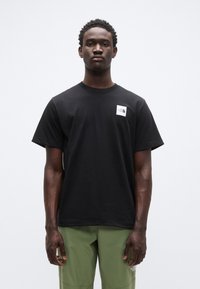 Μα ύρο βαμβακερό t-shirt με κοντά μανίκια, στρογγυλή λαιμόκοψη και λογότυπο στο αριστερό μέρος του στήθους. Με απαλή υφή και άνετη εφαρμογή, συνδυασμένο με πράσινο παντελόνι.