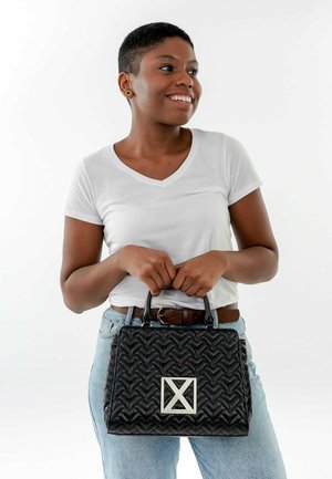 Schwarze geflochtene Handtasche mit silbernen Beschlägen, die ein geometrisches Logo aufweist. Die Tasche hat eine strukturierte Form und kurze Griffe zum Tragen.