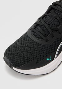 Černá sportovní bota s síťovaným svrškem, doplněná tyrkysovým akcentem a černými tkaničkami. Zaoblená špička s bílou mezipodešví a texturovanou podešví.