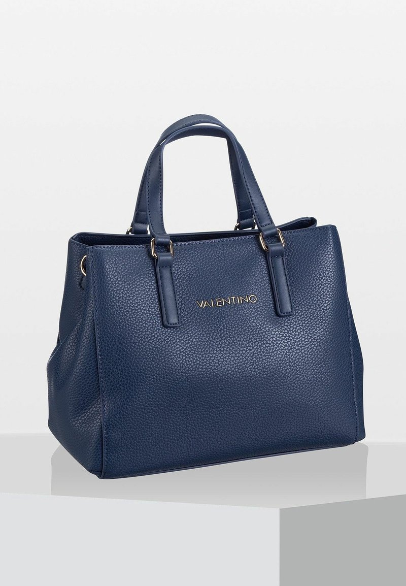 Mörkblå läderhandväska med texturerad yta, strukturerad form, dubbla korta handtag och detaljer i guldton på framsidan.