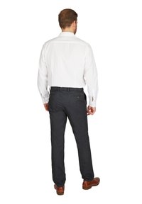 Weißes Hemd mit langen Ärmeln, kombiniert mit dunkelgrauen Hosen. Sichtbare braune Lederschuhe. Die Hose hat Gesäßtaschen.